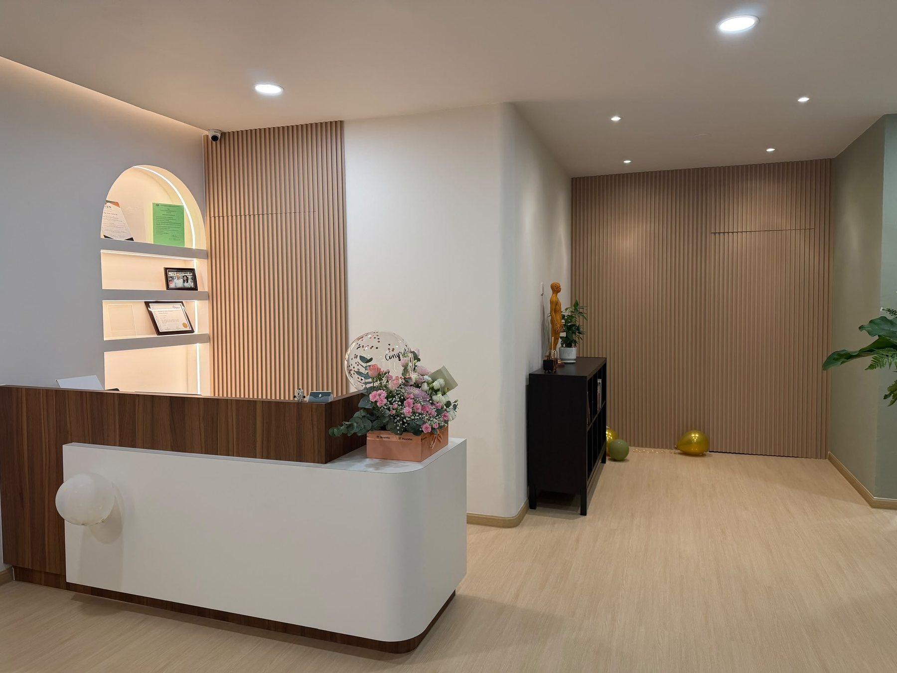 The reception desk at Urban TCM, with an arched, backlit shelf and timber slat walls